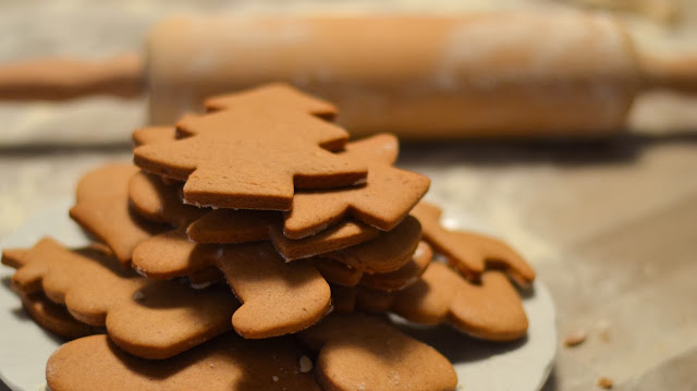 Carved linocut relief print of tree-shaped cookies stacked on a plate, warm brown and cream tones, cozy and homemade